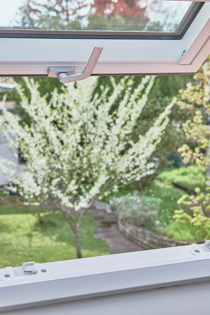 Nahaufnahme eines VELUX-Fensters mit Aussicht auf einen blühenden Baum, der frische Frühlingsluft symbolisiert.