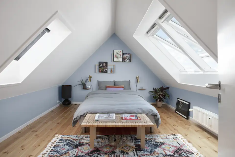 Chambre lumineuse avec fenêtres de toit VELUX, murs bleu clair et mobilier épuré