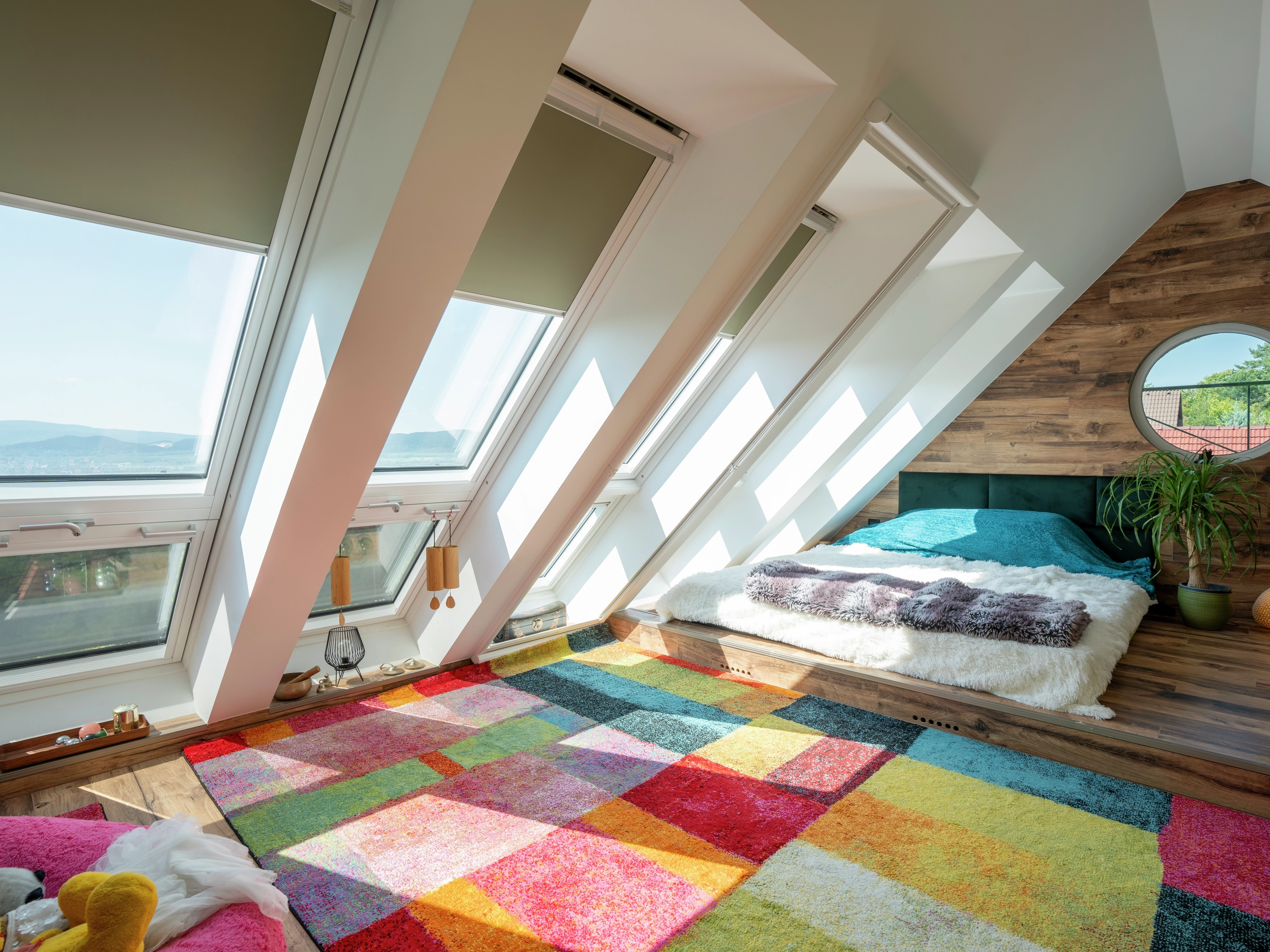 Attic bedroom with colorful rug, sloped ceiling, and VELUX roof windows.