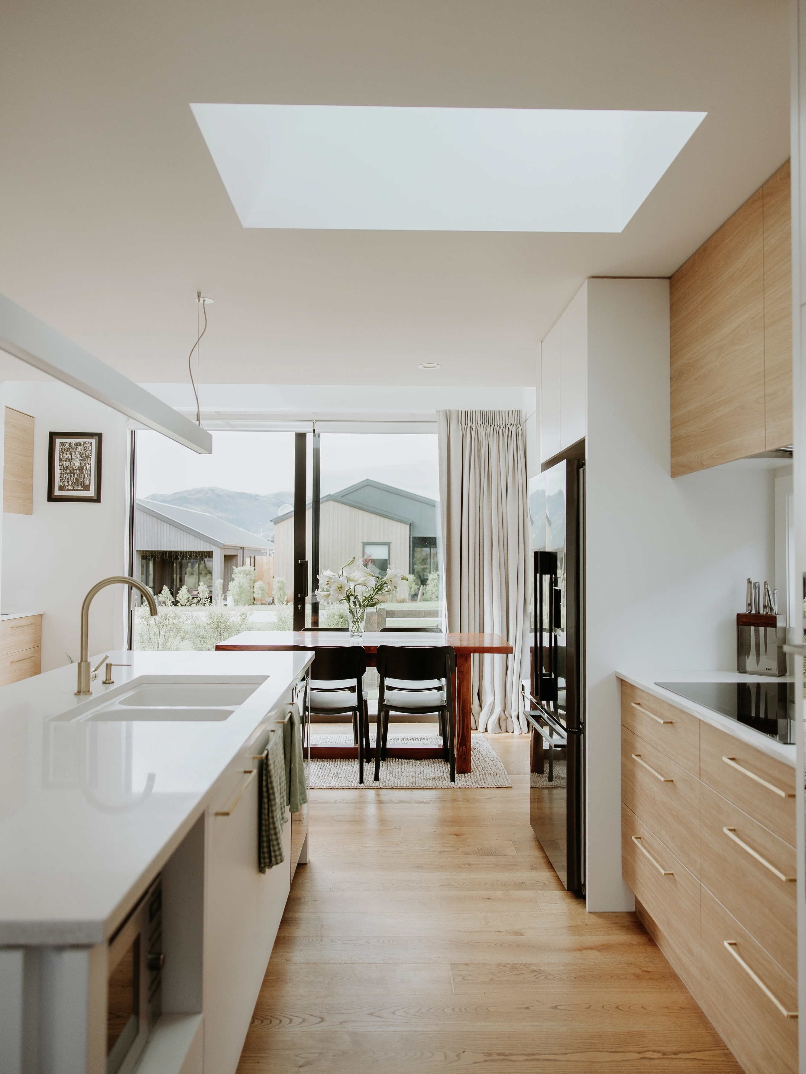 Modern kitchen and dining area lit by a large VELUX flat roof window above the island.
