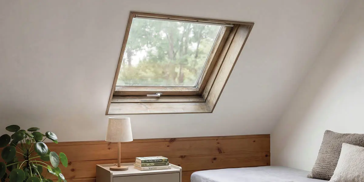 chambre mansardée avec plafond en pente et ancienne fenêtre de toit VELUX