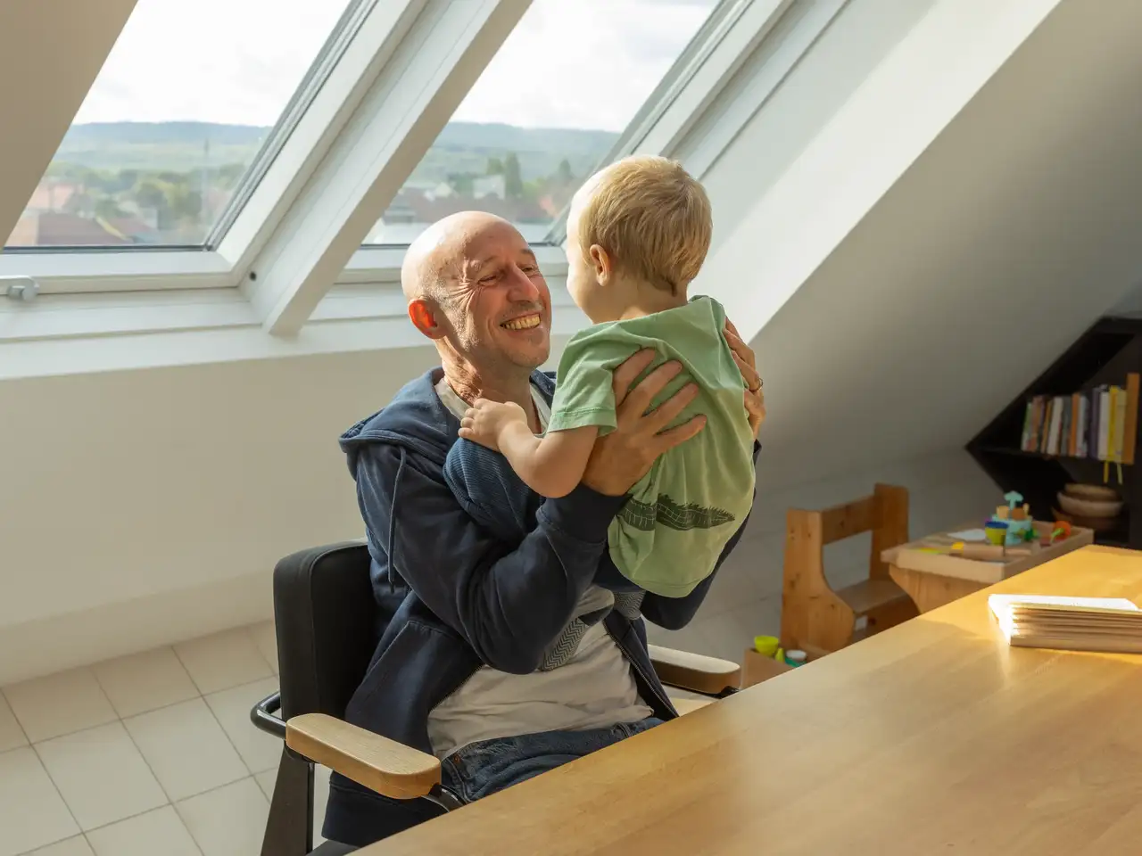 Il padre si siede con il figlio al lucernario e si gode la luce del giorno | Rivista VELUX