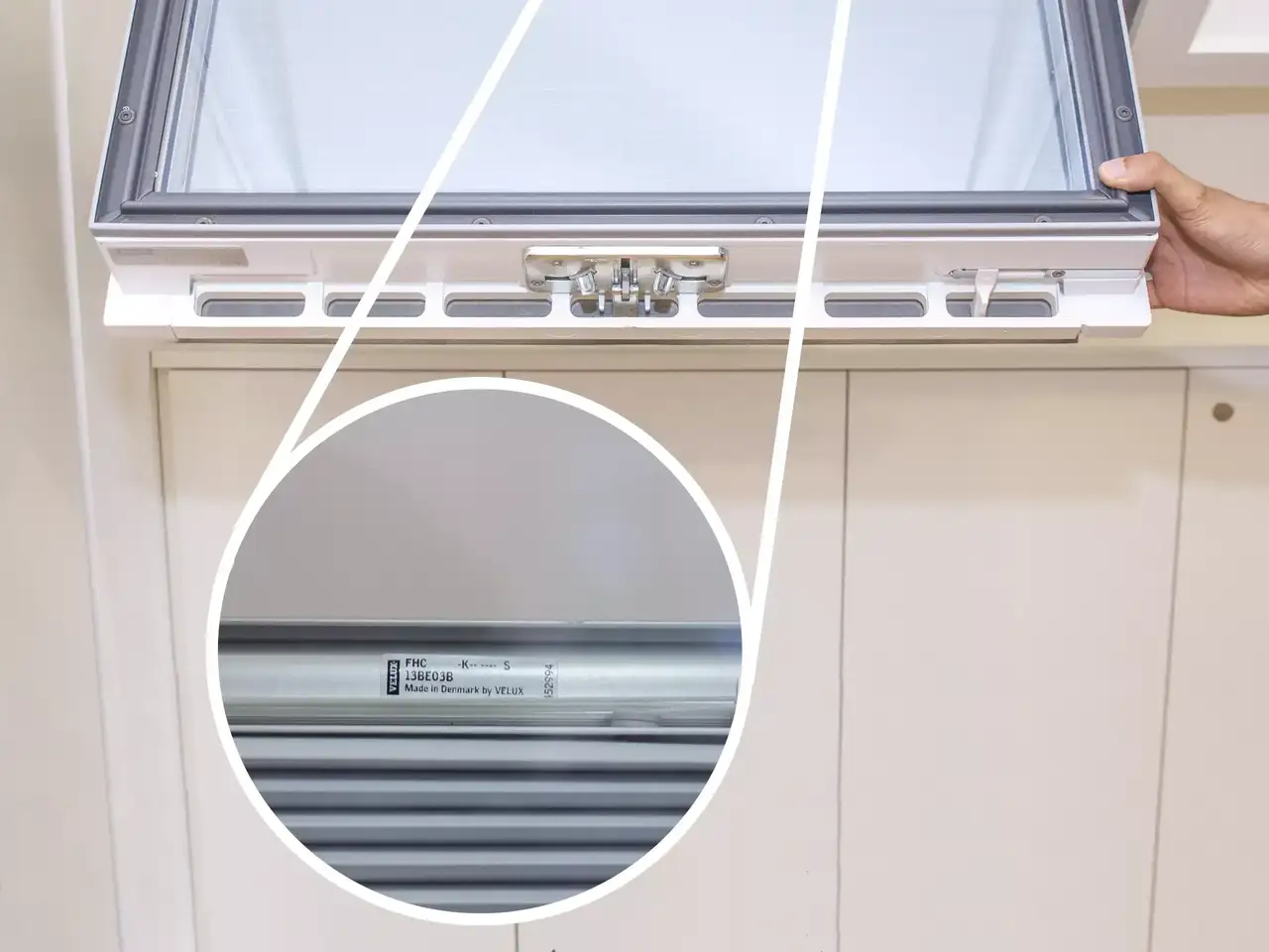 Nahaufnahme des Öffnungsmechanismus eines VELUX-Dachflächenfensters und des Etiketts mit der Aufschrift „Hergestellt in Dänemark von VELUX“.