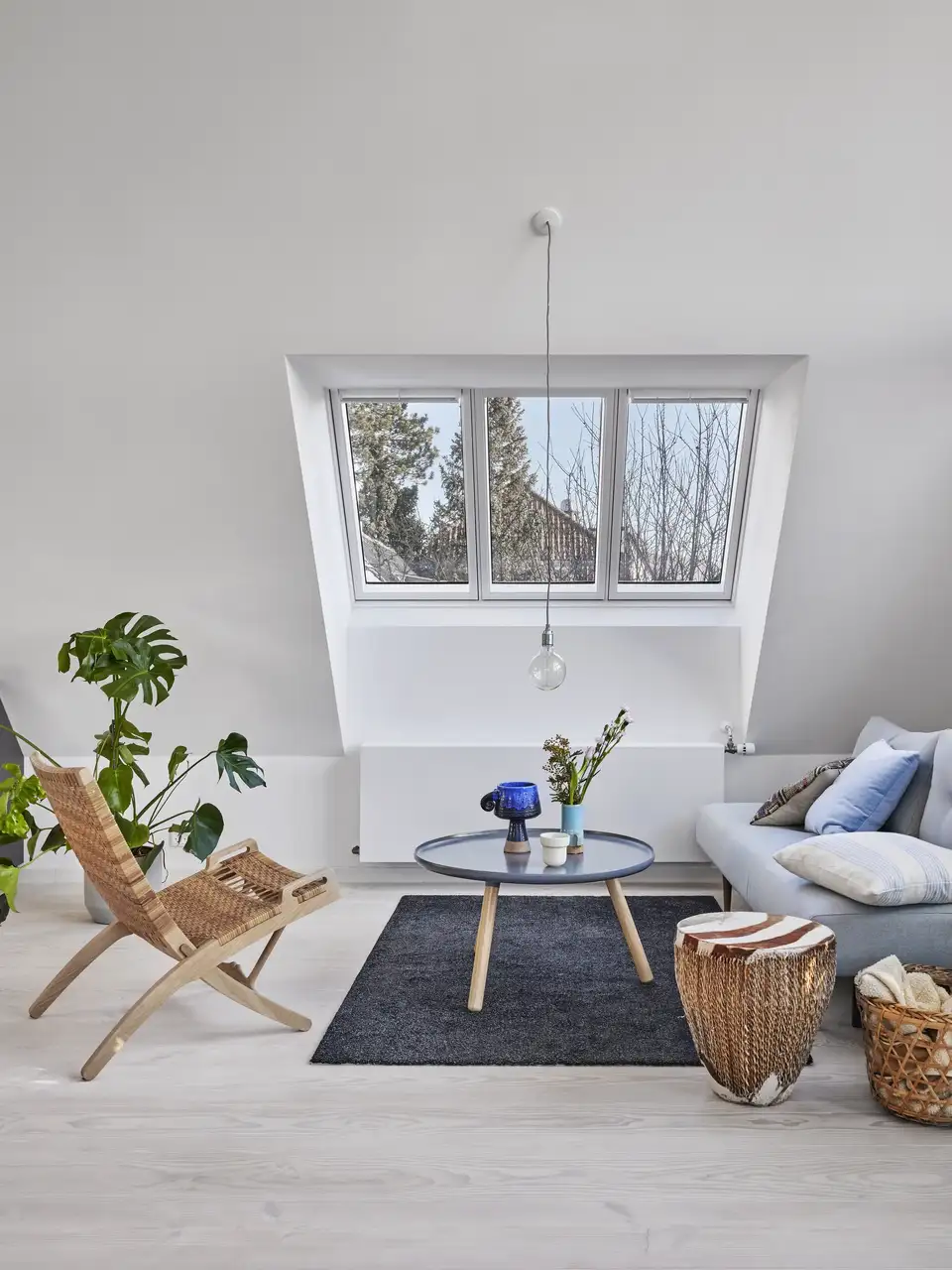 Espace détente avec canapé, fauteuil et table basse sous une verrière VELUX 3-en-1. 