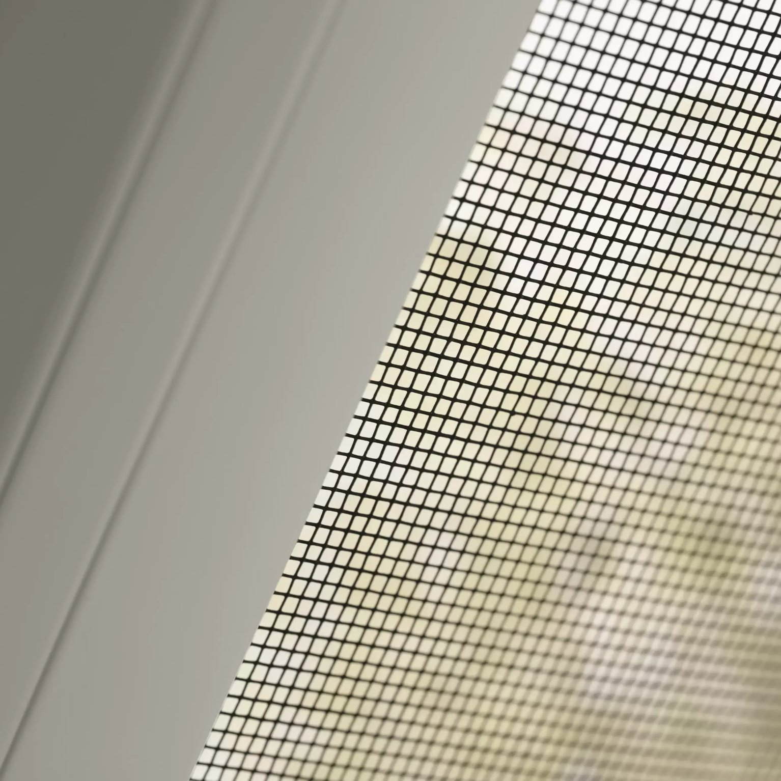 Close-up of window screen mesh pattern against blurred background.