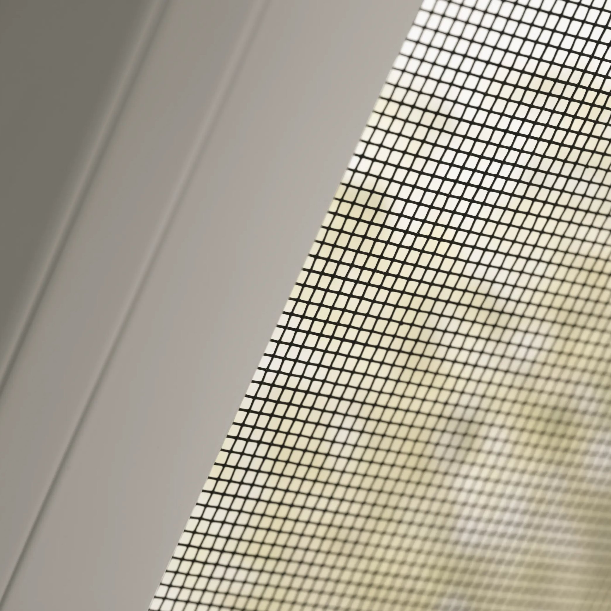 Close-up of window screen mesh pattern against blurred background.