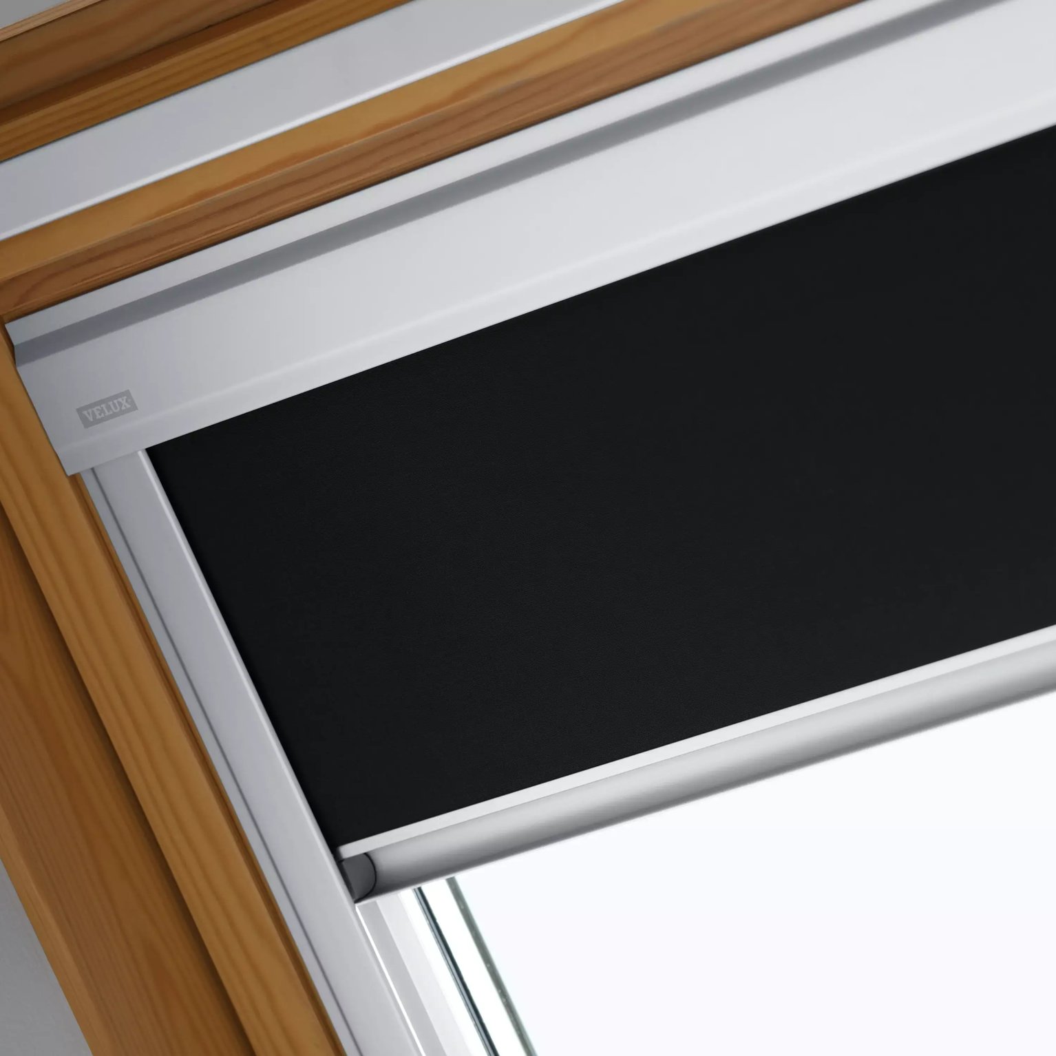 Close-up of VELUX roof window with black blind and wooden frame.