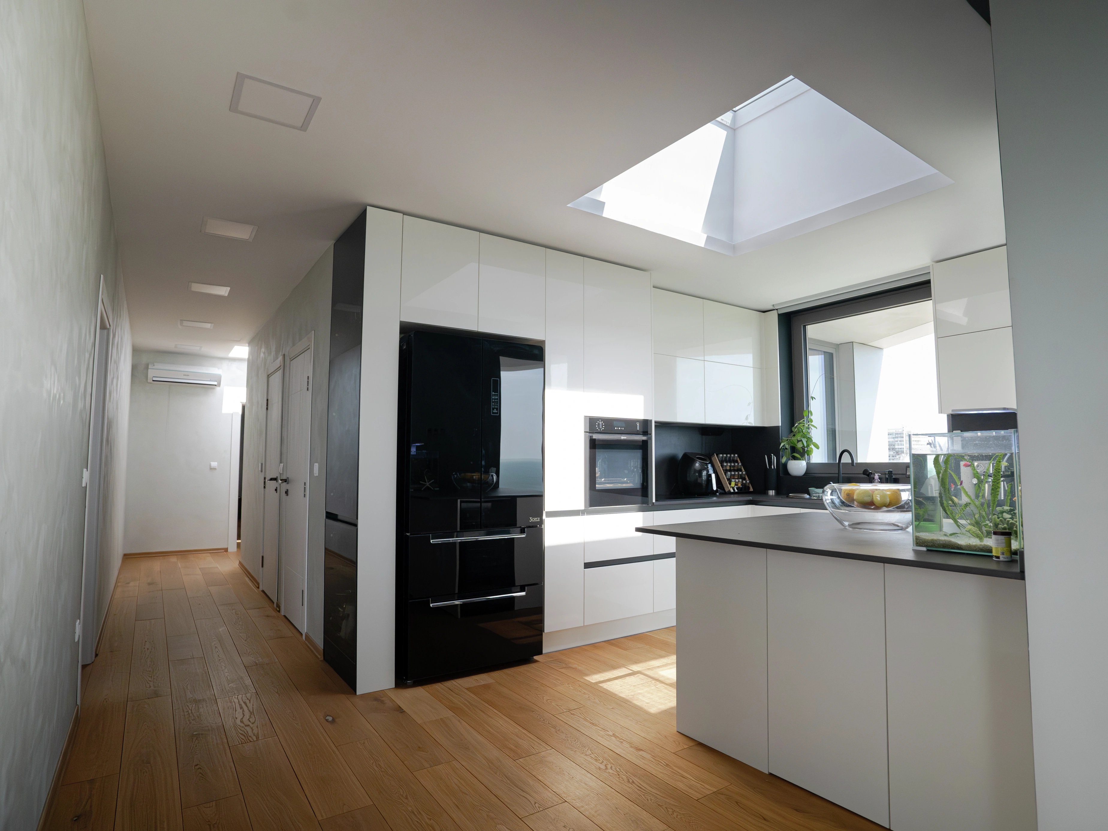 Modern white kitchen with VELUX flat roof window bringing daylight onto the island.
