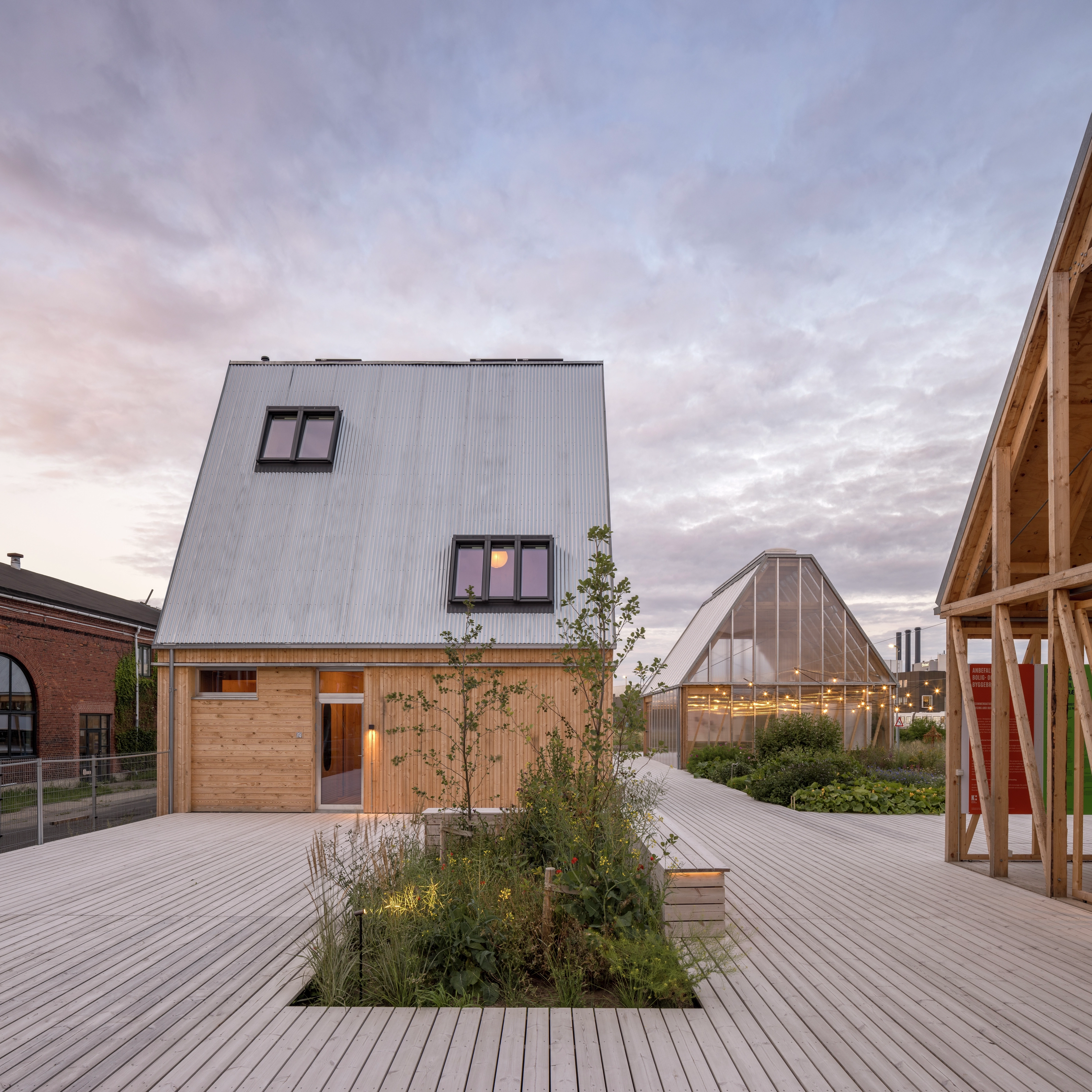 Wooden house with metal roof and large windows, evening sky backdrop.