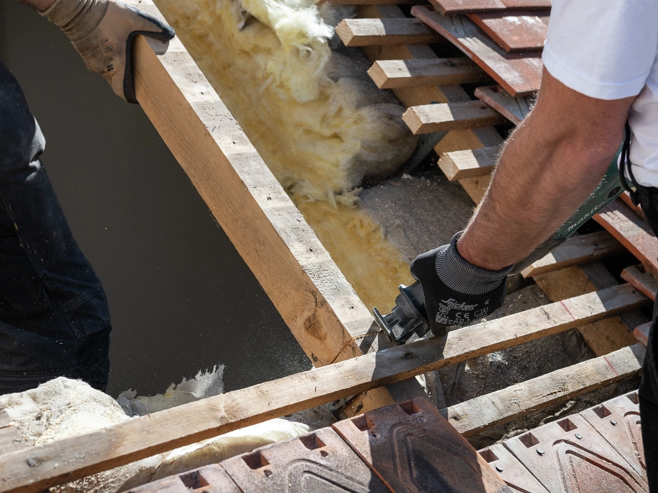 Darbininkai deda izoliacinę medžiagą ir medines sijas ant stogo konstrukcijos. | VELUX