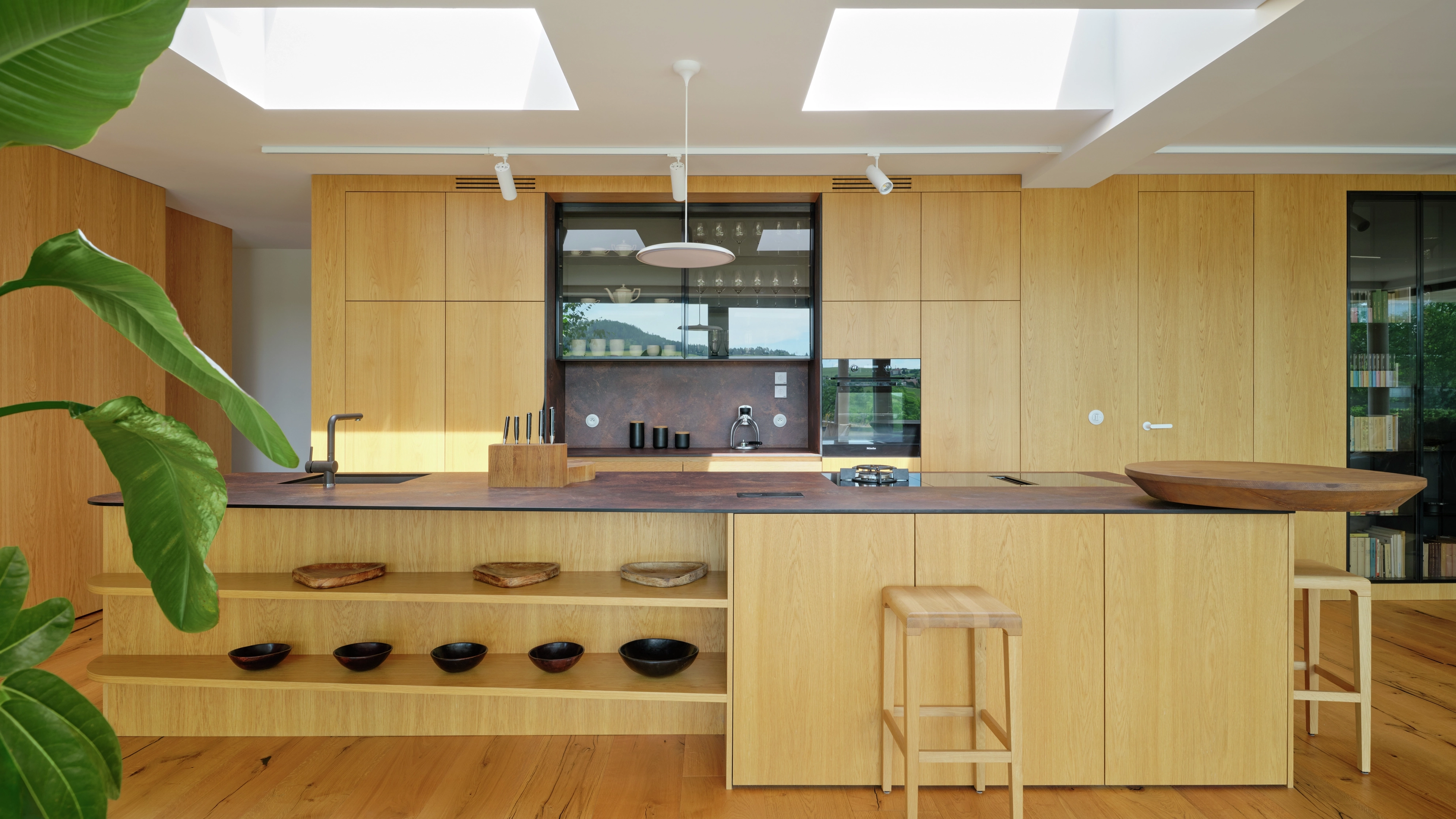 Modern wooden kitchen island lit by two VELUX flat roof windows above.