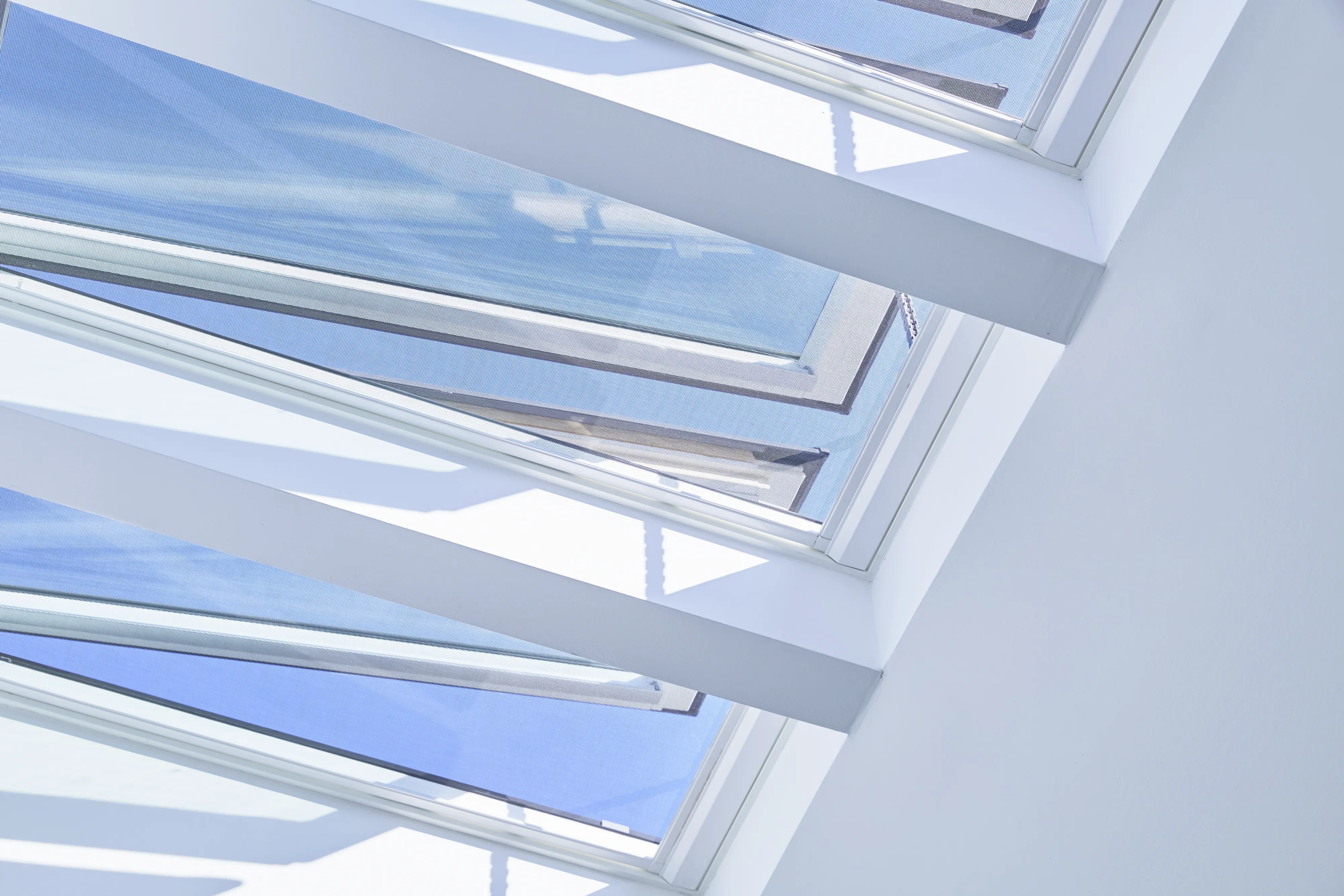 Ferestre de mansardă VELUX deschise pe tavan înclinat, interior luminos și aerisit.