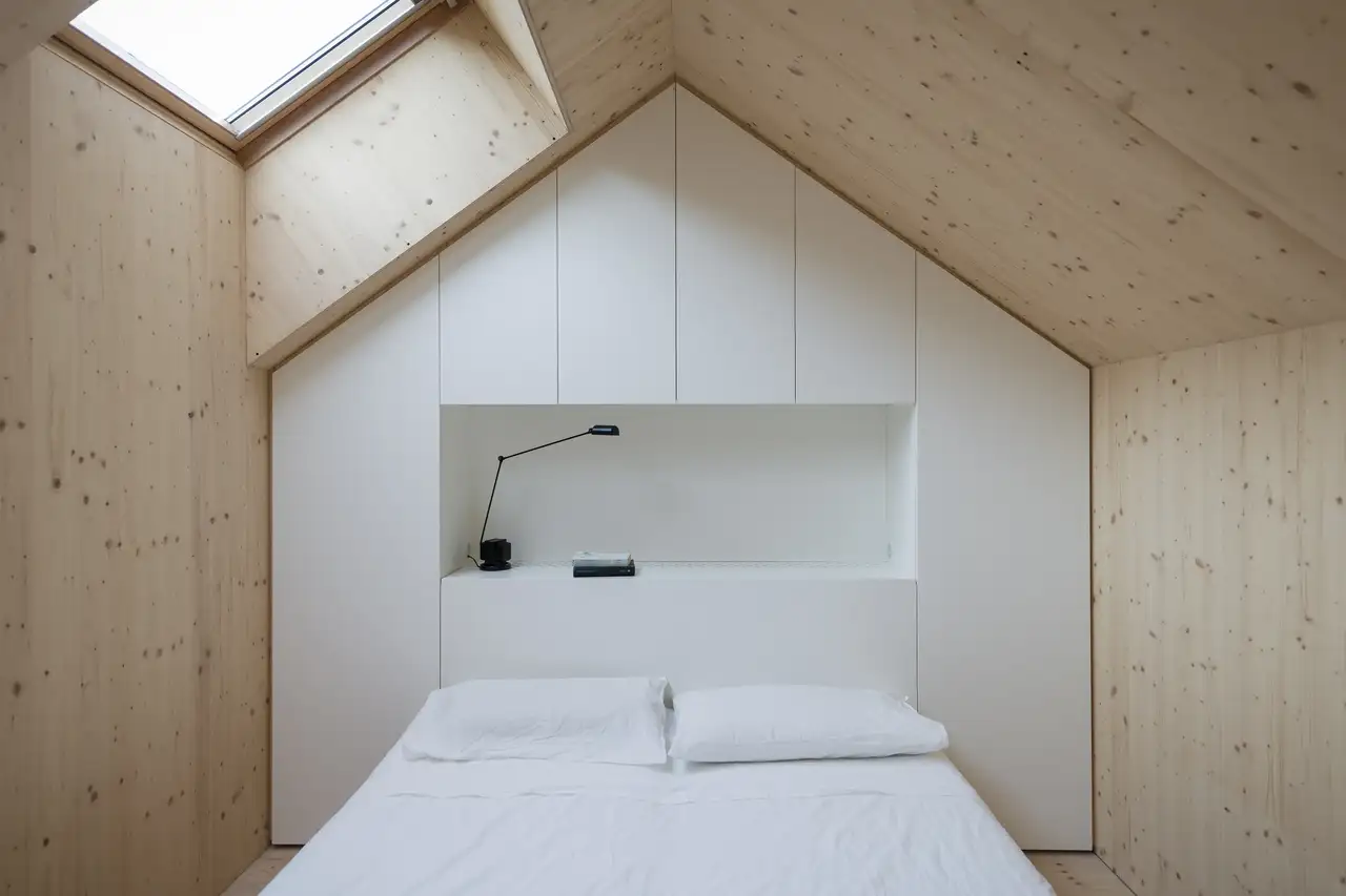 chambre minimaliste avec murs en bois brut et placards intégrés sans poignées