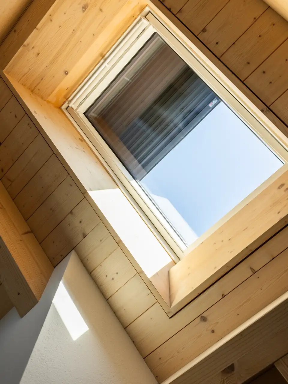 Soffitto in legno e finestra per tetti VELUX con tapparella parzialmente chiusa.