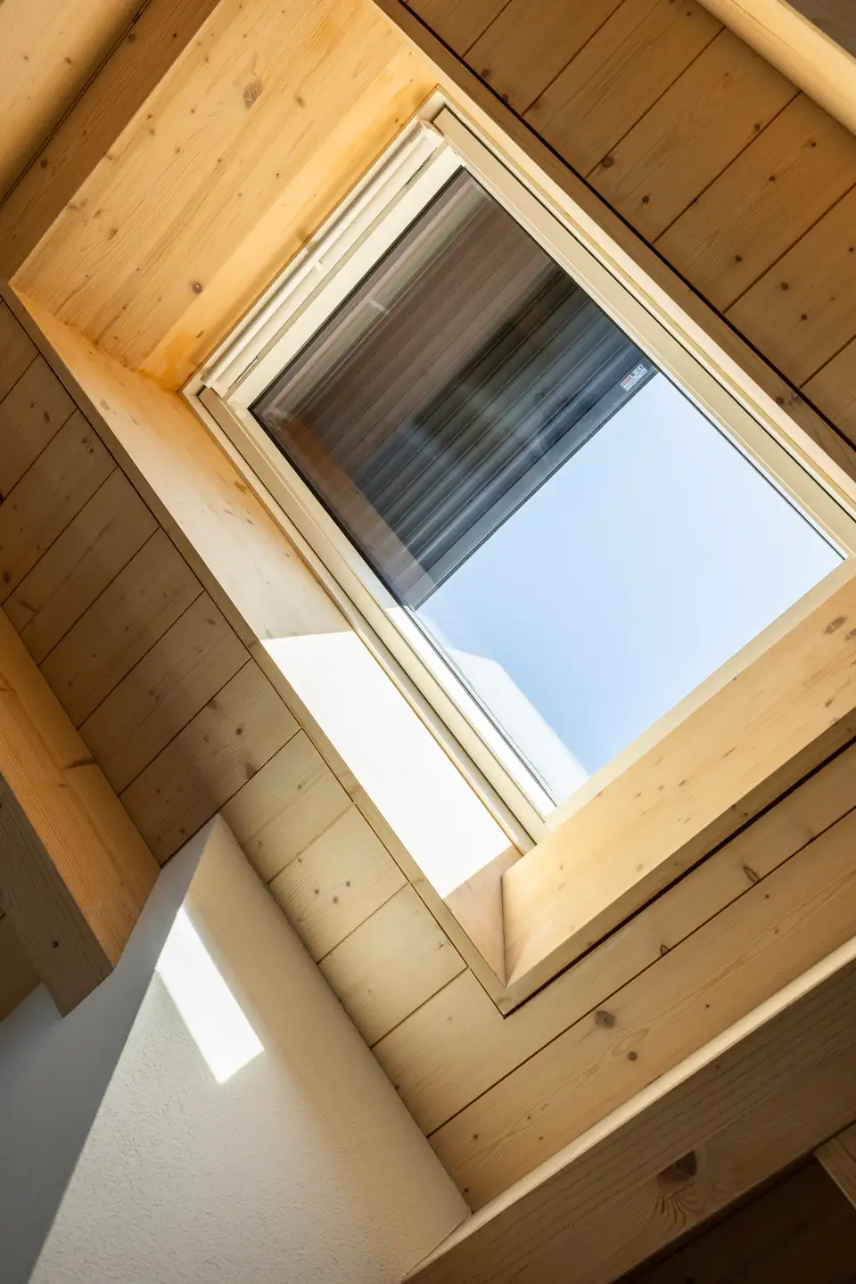 plafond en bois et fenêtre de toit VELUX avec volet roulant partiellement fermé