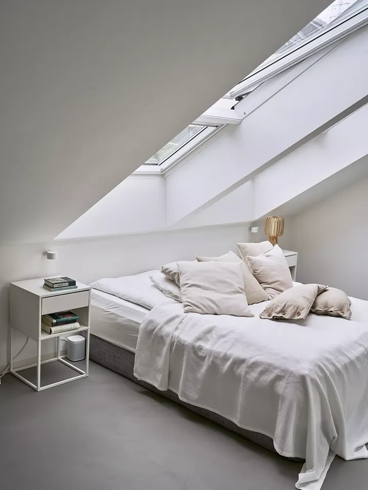 Minimalistisches Dachboden-Schlafzimmer mit VELUX Dachflächenfenstern und gemütlicher Bettwäsche.
