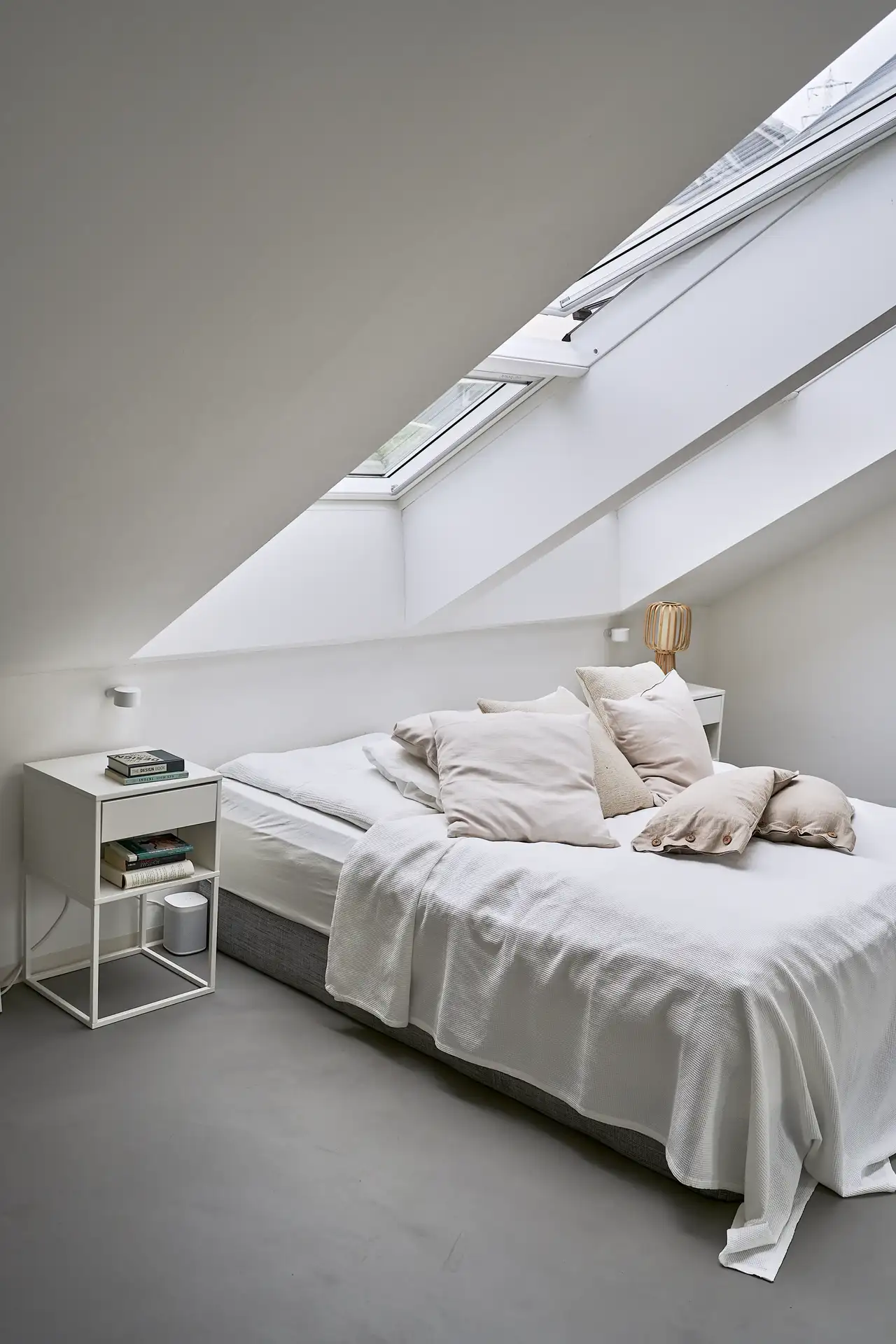 Bett direkt unter der Daschräge inmitten eines cremefarbenen Dachzimmers  | VELUX Magazin