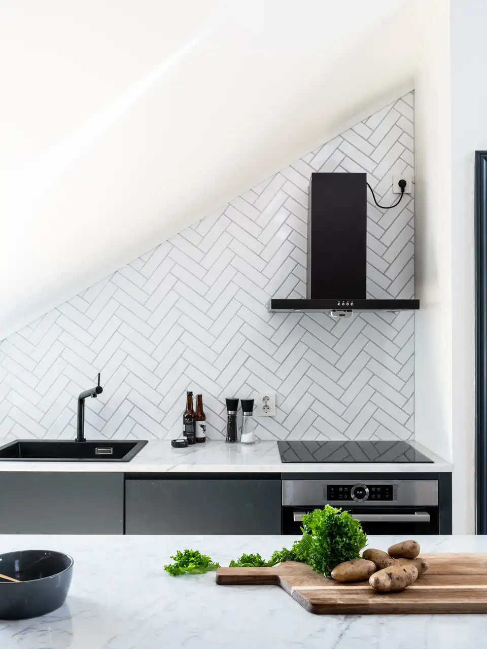 Cucina moderna con paraschizzi bianco tipo metro e finestra per tetti che illumina il piano di lavoro