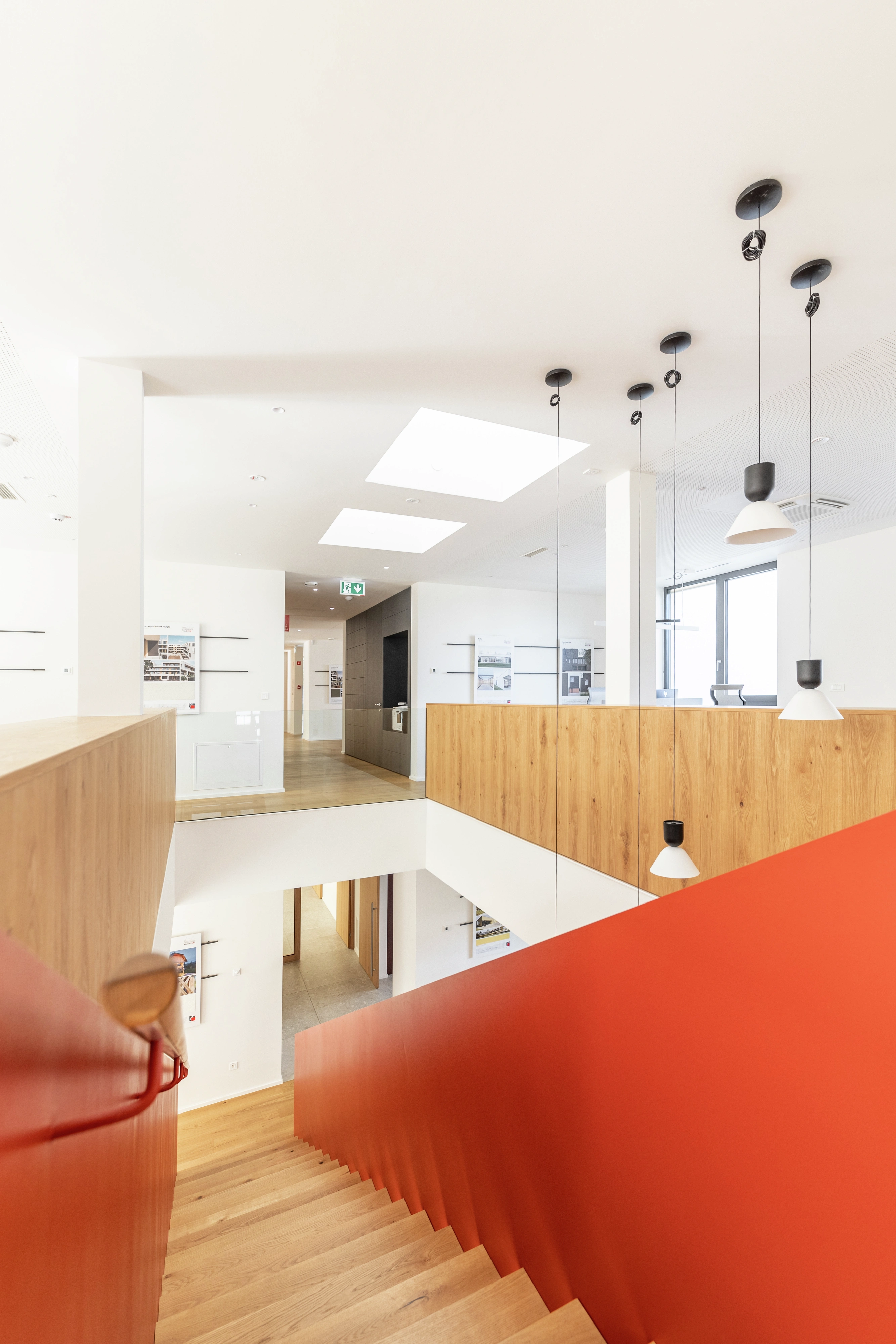 Moderní kancelářský interiér s červeným schodištěm, přirozeným světlem a střešními okny VELUX