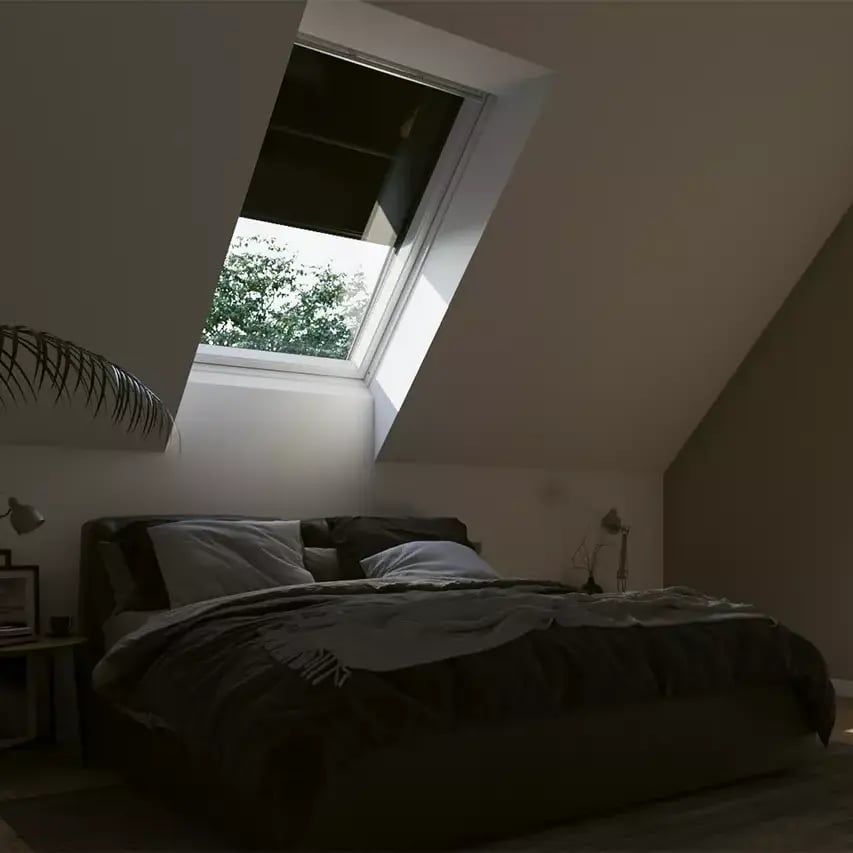 Attic bedroom with sloped ceiling and VELUX roof window, cozy and tranquil.