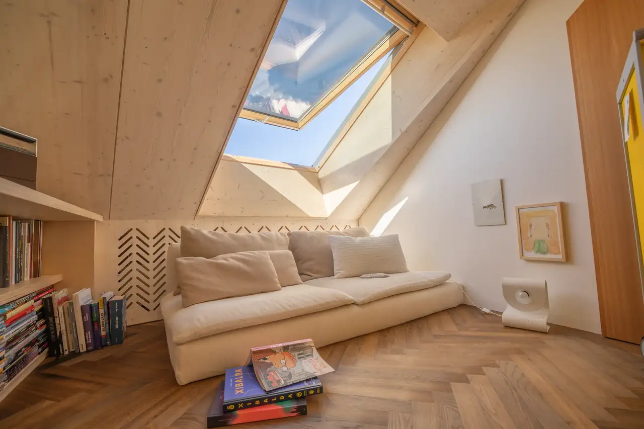 Helle Couch auf Holzfussboden unter grossem Dachfenster | VELUX Magazin