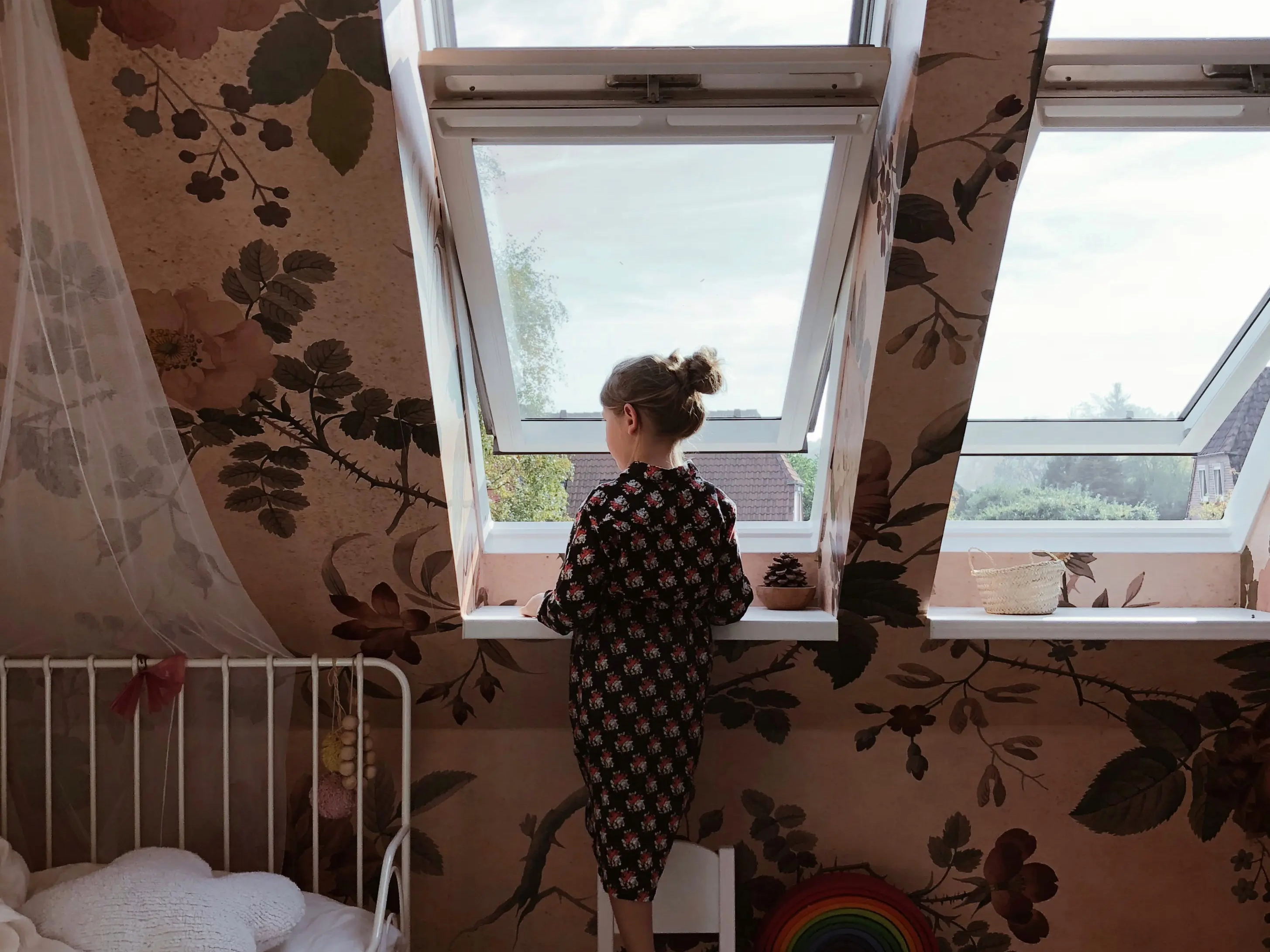 Mädchen guckt aus Dachfenster im Kinderzimmer | VELUX Magazin