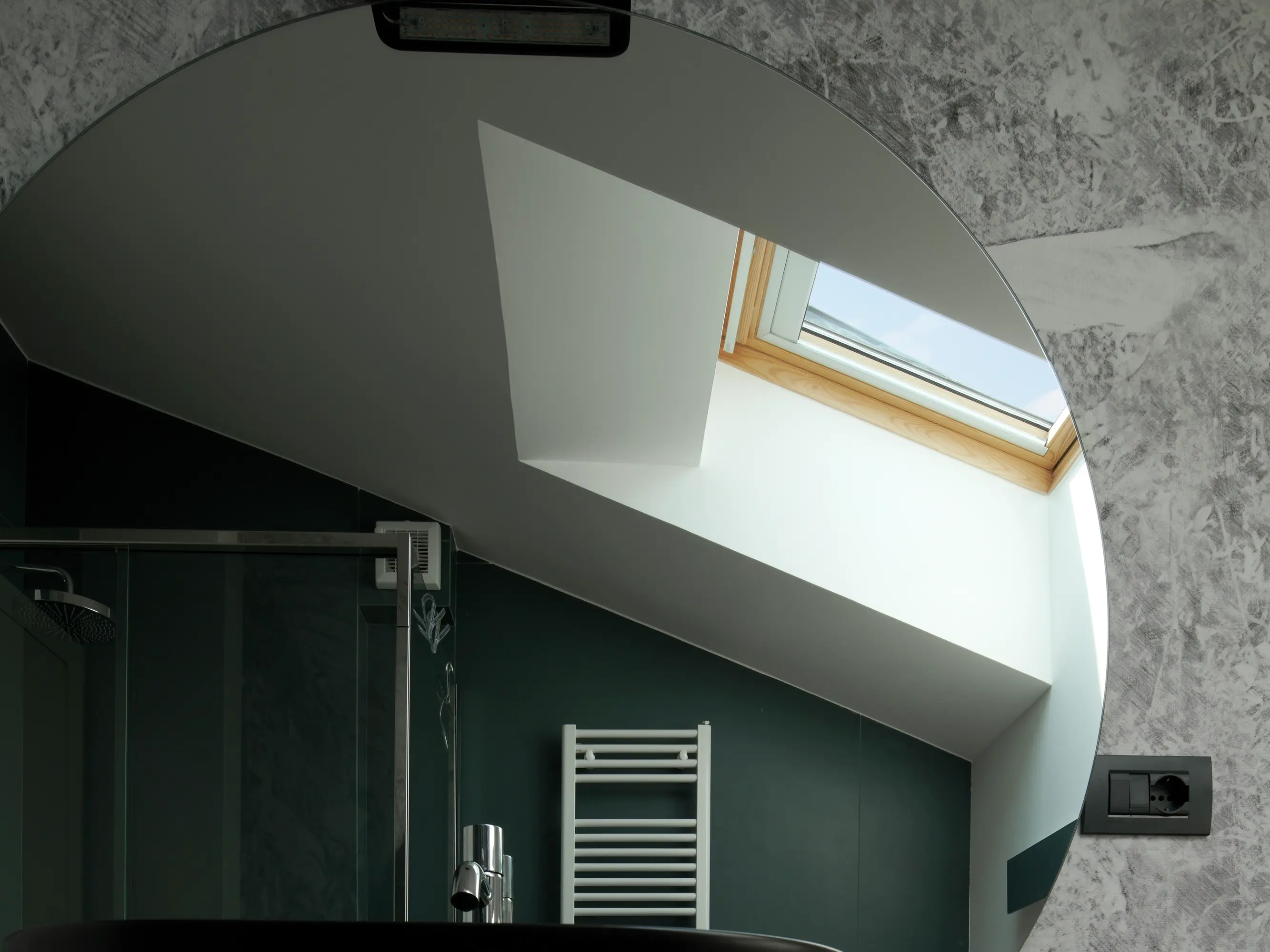 Salle de bain moderne avec une fenêtre de toit VELUX offrant une lumière naturelle.