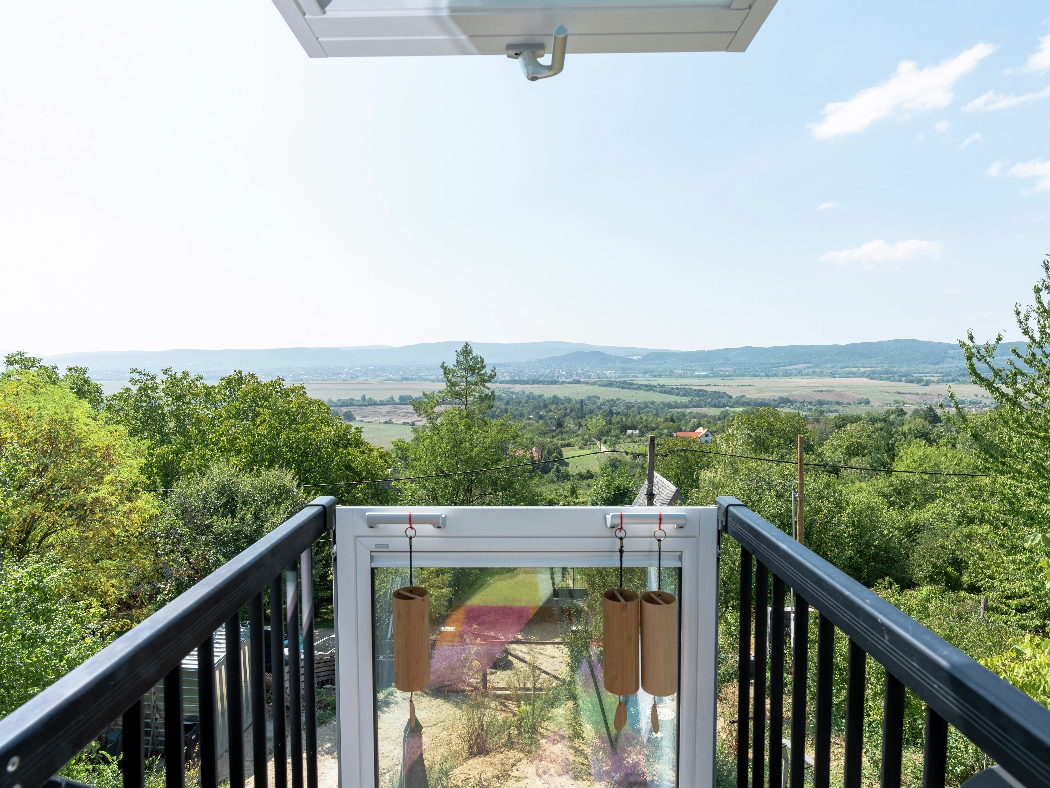 Open VELUX roof window with a scenic view of the countryside and distant hills.