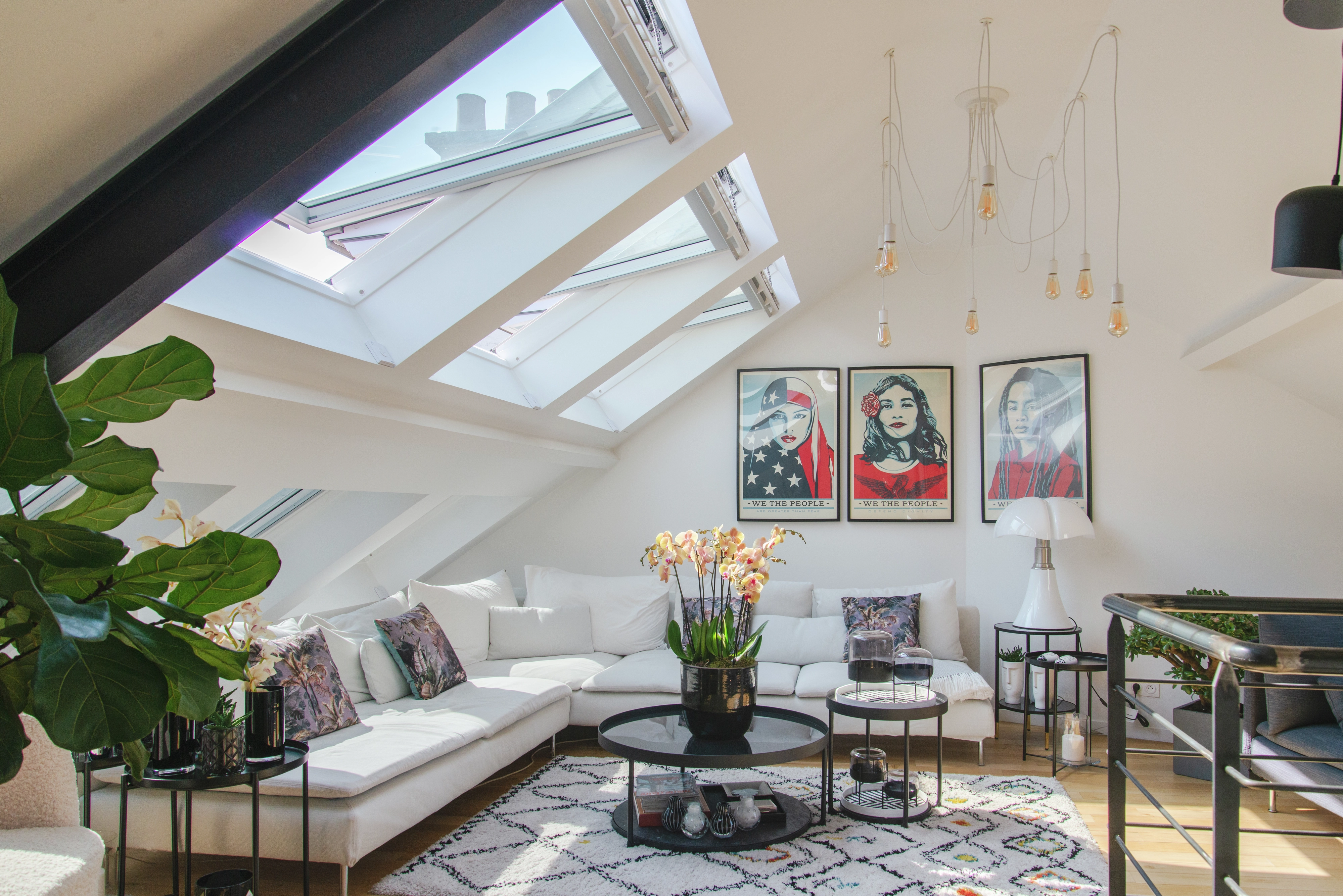 Attic living room with VELUX roof windows, white sofa, and artwork.