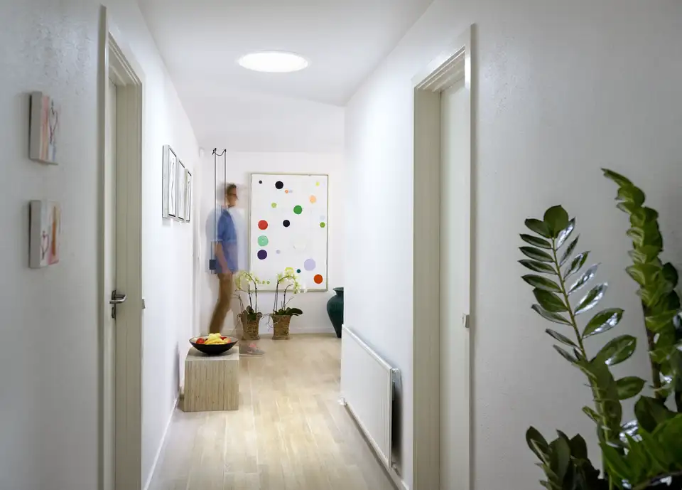 Couloir contemporain éclairé par un tunnel solaire VELUX diffusant une lumière uniforme. 