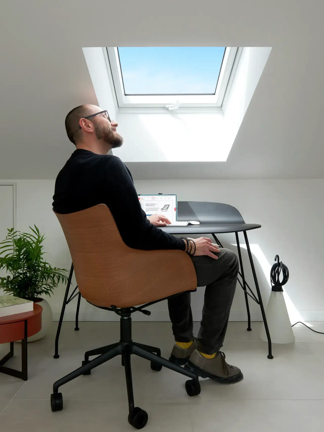 Homme regardant le ciel à travers la fenêtre de toit VELUX de son espace de travail 