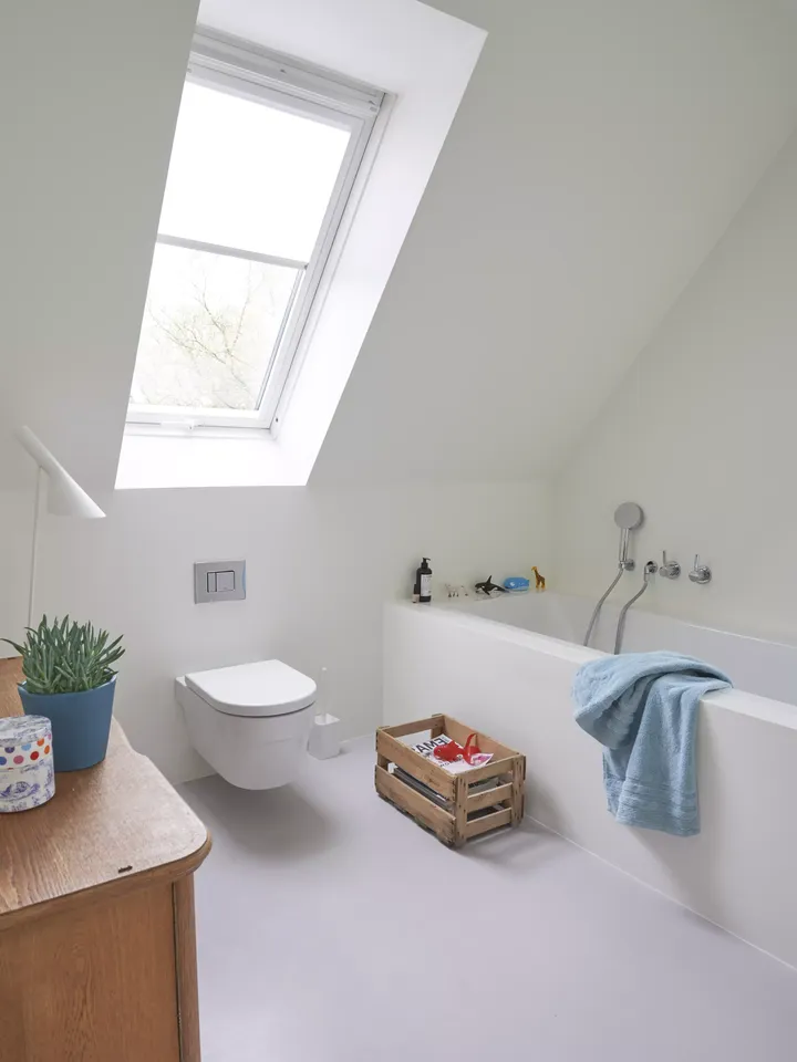 Modernes Badezimmer mit natürlichem Licht von einem VELUX Dachflächenfenster, weißen Einrichtungsgegenständen und hölzernen Details.