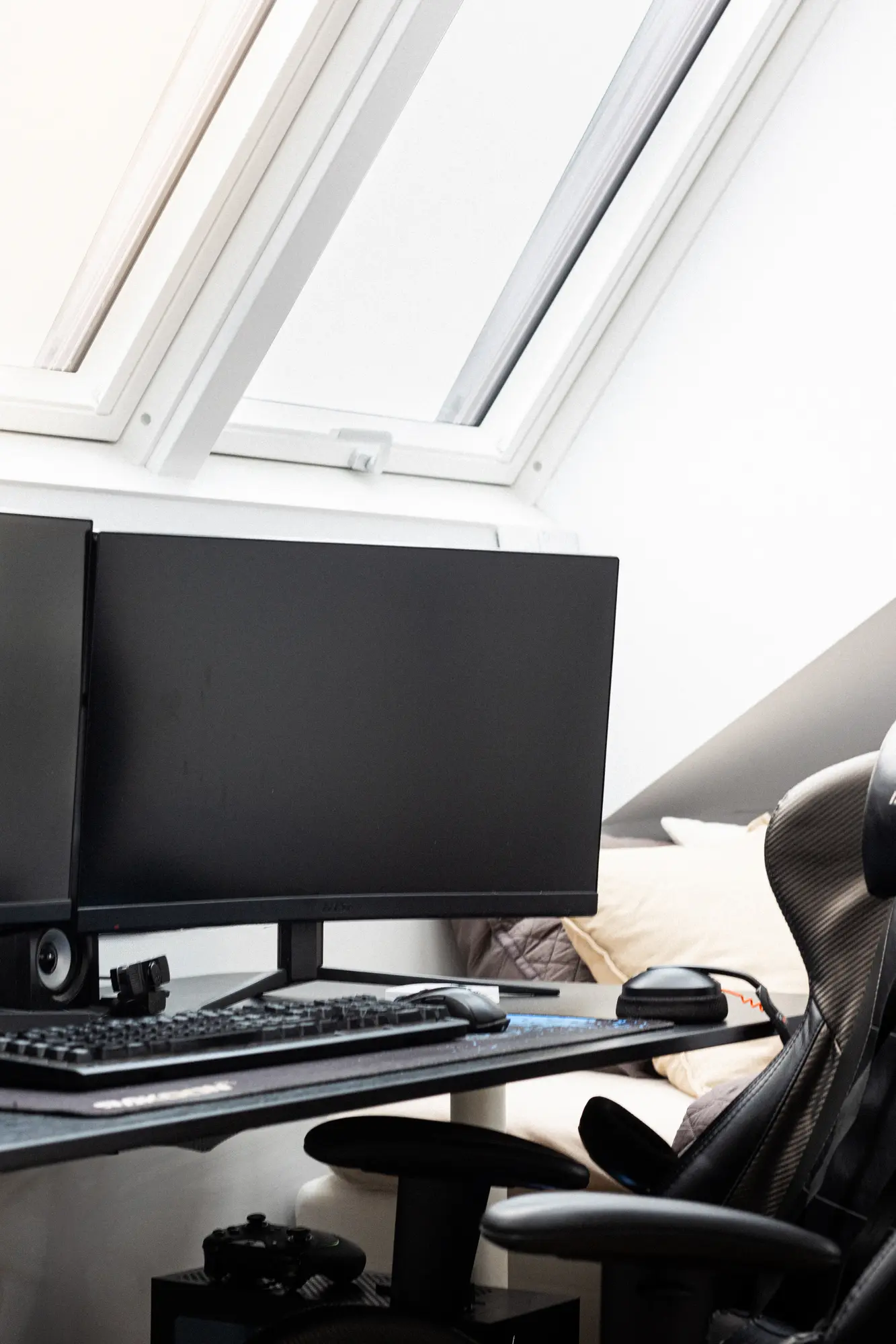 Attic home office with dual monitors and a VELUX roof window.