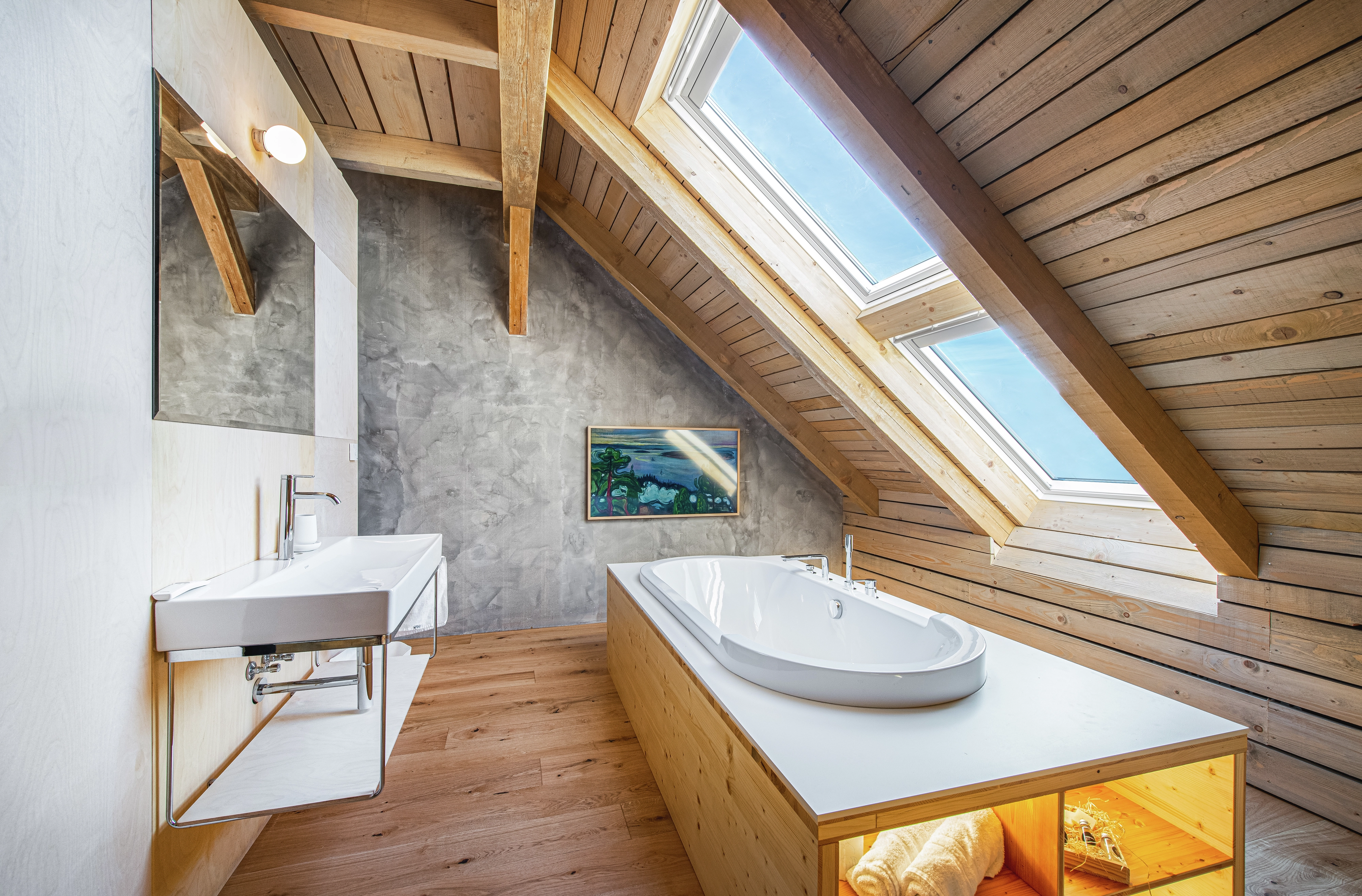Attic bathroom with sloped ceiling, VELUX roof window, modern sink and bathtub.