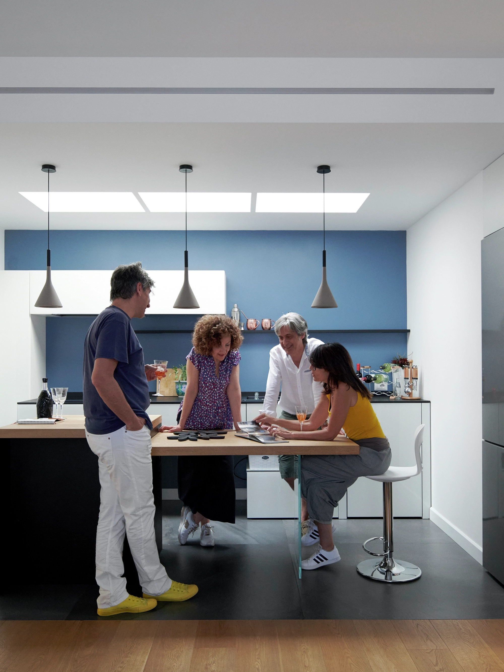 Modern kitchen with people gathered around a central island.