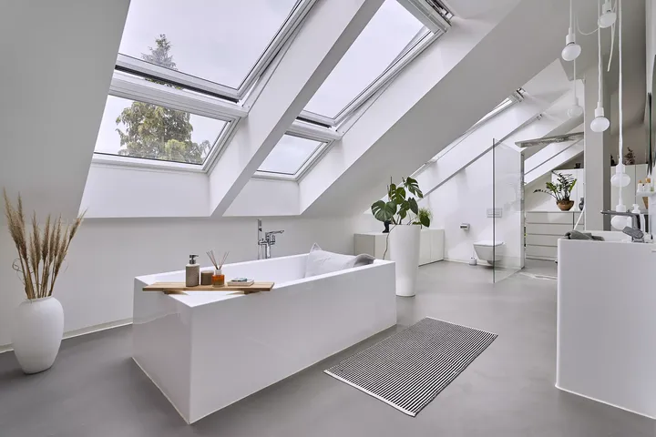 Helles modernes Badezimmer mit VELUX Dachflächenfenstern und freistehender Badewanne.