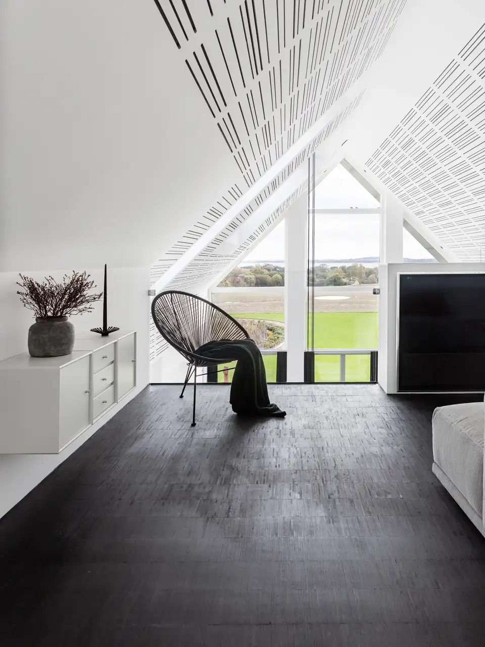 Salon minimaliste noir et blanc avec fauteuil design et grandes fenêtres de toit.  