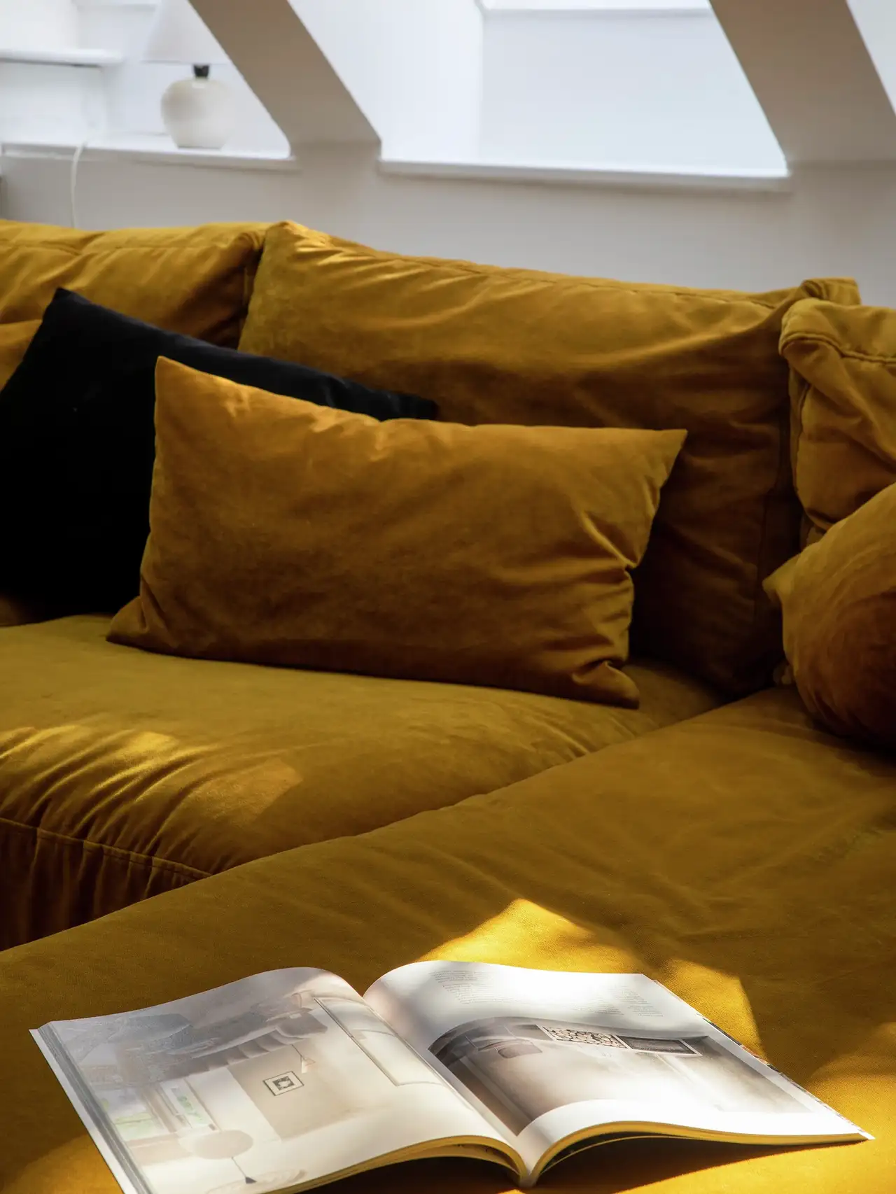Attic living space with mustard sofa and VELUX roof window.