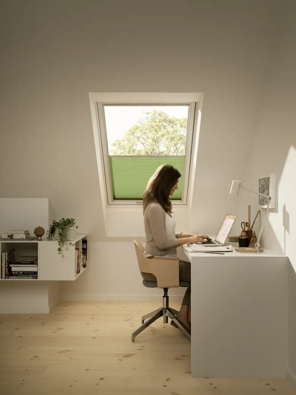 Bureau sous combles équipé d’une fenêtre de toit VELUX et d’un store plissé tamisant.