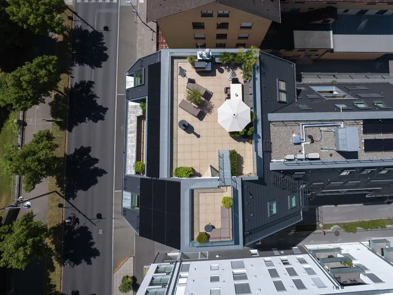 Vista aerea di una moderna terrazza sul tetto con posti a sedere, ombrellone e piante 