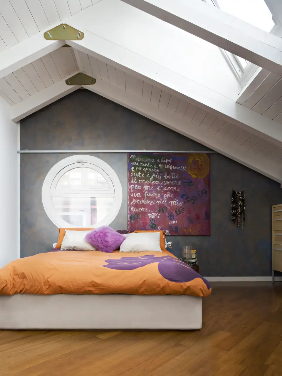 Chambre sous les toits avec fenêtres de toit VELUX, mur bleu profond et linge de lit orangé, de style Dopamine decor.