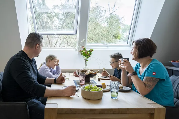 Familie versammelt sich um den Esstisch mit natürlichem Licht von einem VELUX-Fenster.