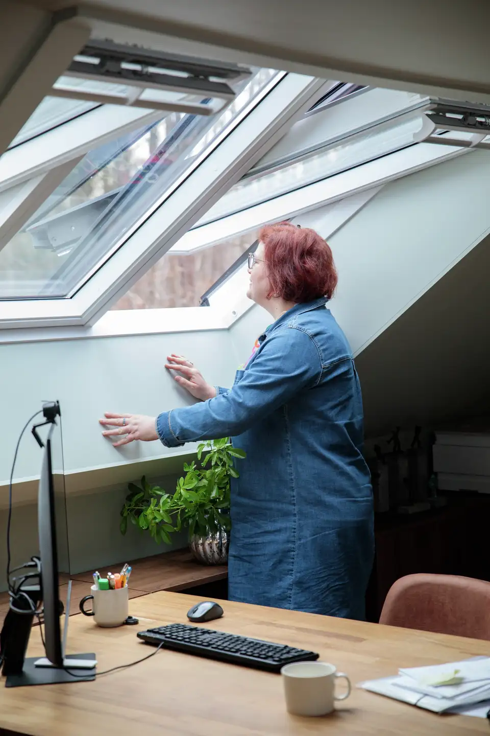 Vrouw kijkt door een VELUX dakvenster in haar werkruimte
