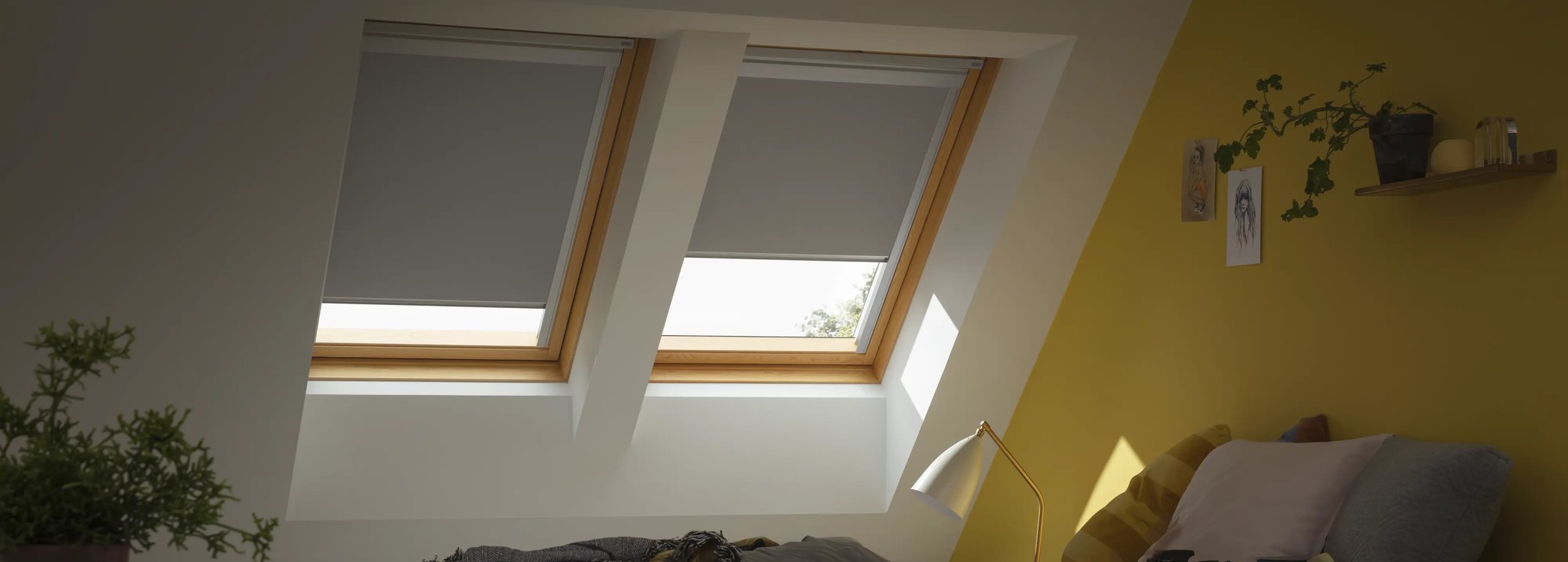 Attic bedroom with sloped ceiling and VELUX roof windows, cozy decor.
