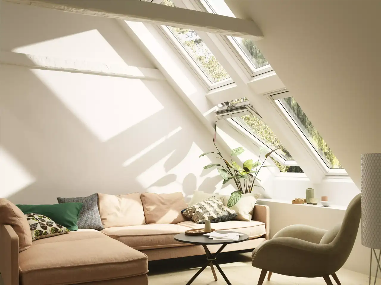 Gemütliches Wohnzimmer im Dachboden mit natürlichem Licht von VELUX Dachflächenfenstern, bequemem Sofa und grünen Pflanzen.