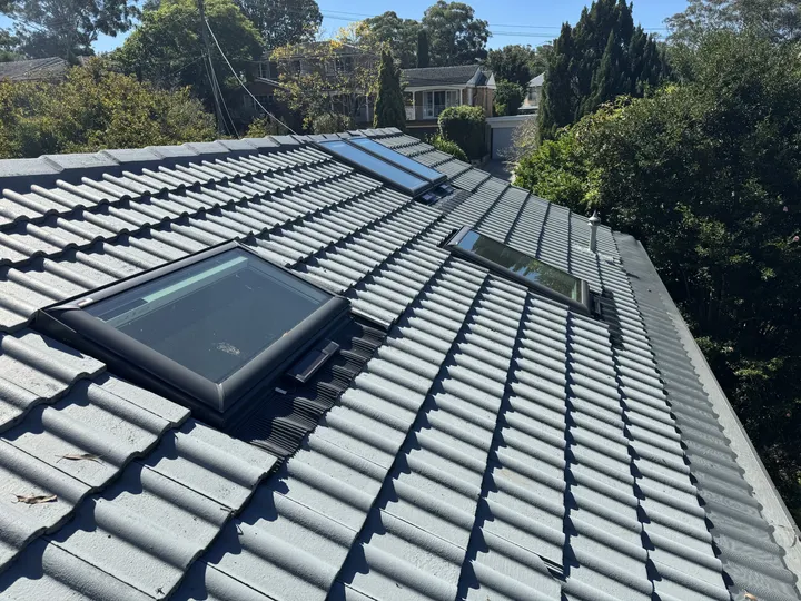 Tiled roof with VELUX roof windows under sunny sky.