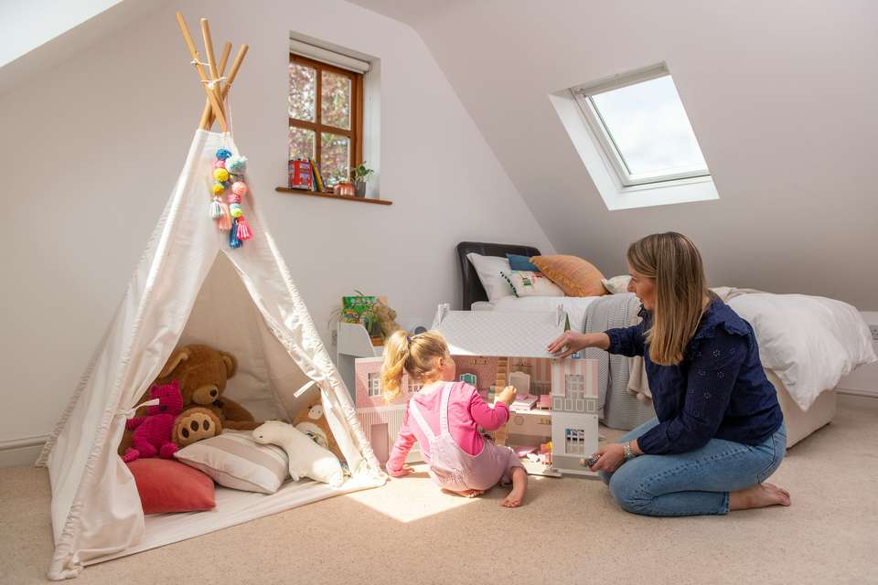Femme et enfant jouant dans une chambre lumineuse avec fenêtre verticale et fenêtre de toit VELUX