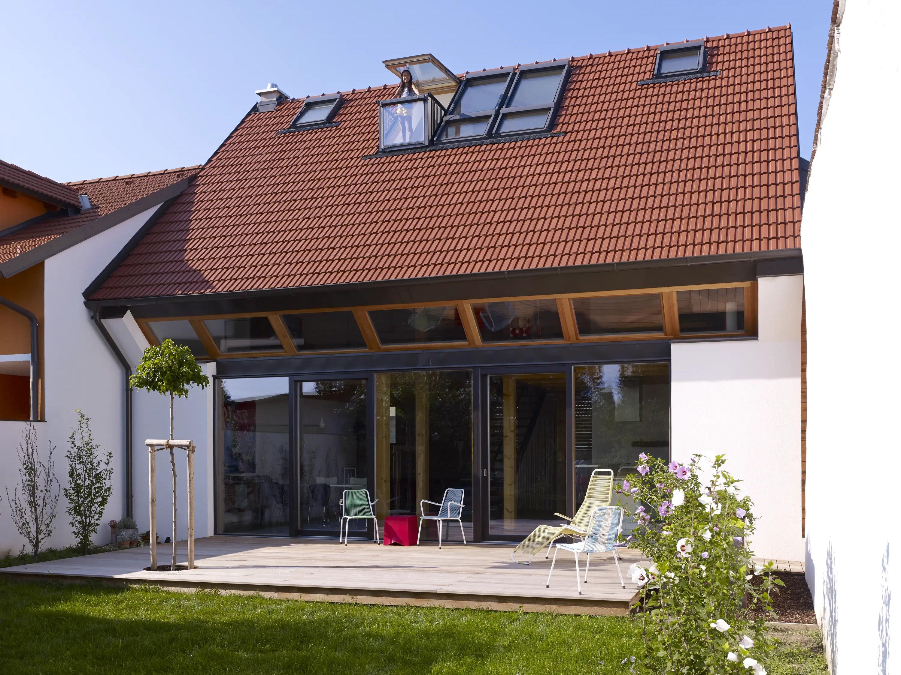 Modern house with red tile roof and open VELUX roof window.