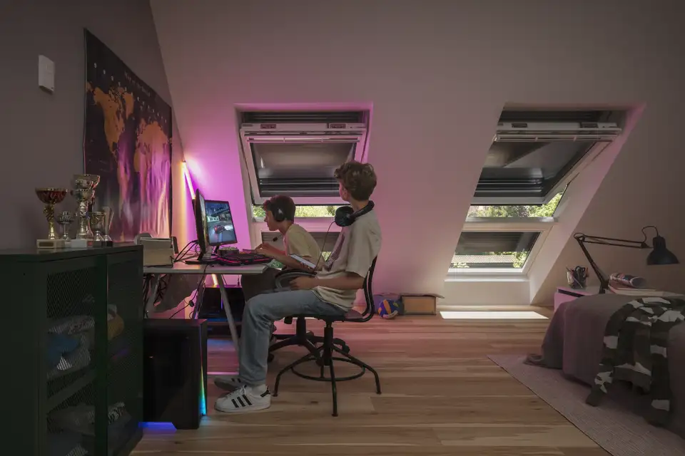 Cameretta in mansarda con finestre per tetti con tapparelle chiuse e una striscia LED luminosa. 