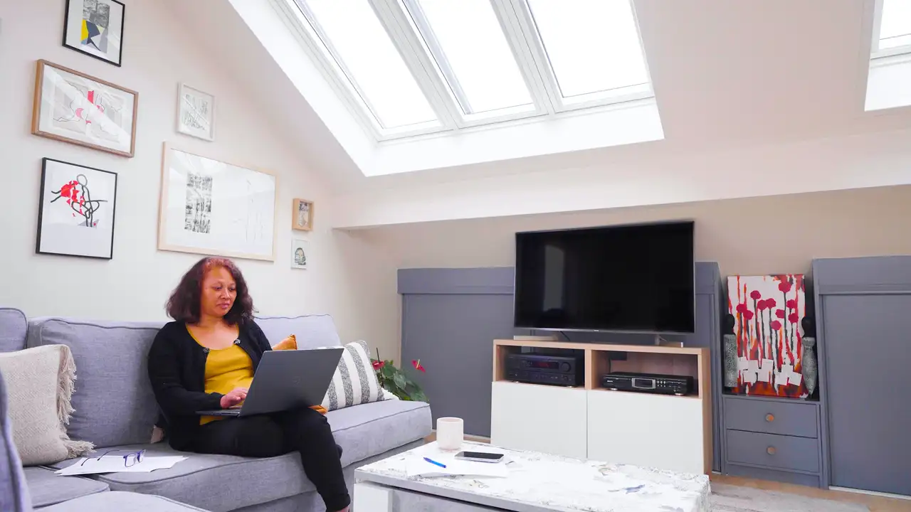 Une femme travaille sur un canapé sous une verrière VELUX